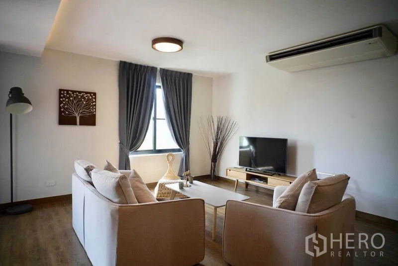 Condominium for rent in Watthana, Bangkok - Living area with sofa set, TV and floor lamp under ceiling lights.