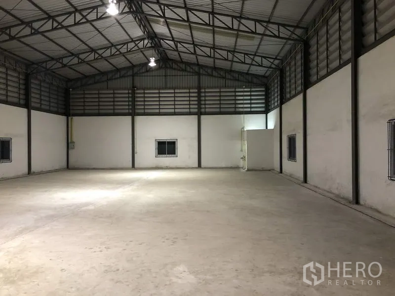 货栈 出租在Lam Luk Ka, Pathum Thani - 夜间照明良好的仓库，混凝土地面，高尖顶屋顶与设备间。