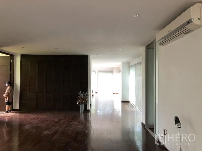 Factory for rent in Pathum Thani - Long hallway with wood flooring, built-in dark wood storage and split-type air conditioner.