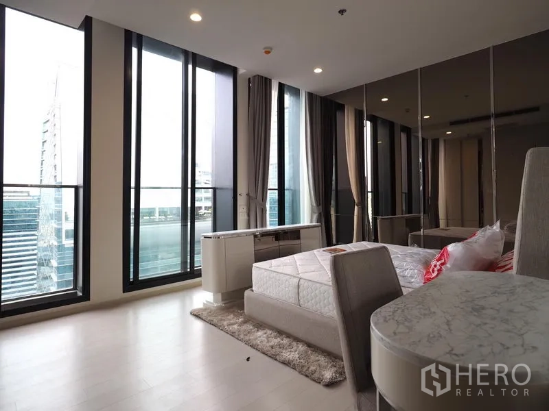 Condominium for rent in Pathum Wan, Bangkok - Bedroom featuring tall glass panels, balcony outlook, mirrored wardrobes and city views.