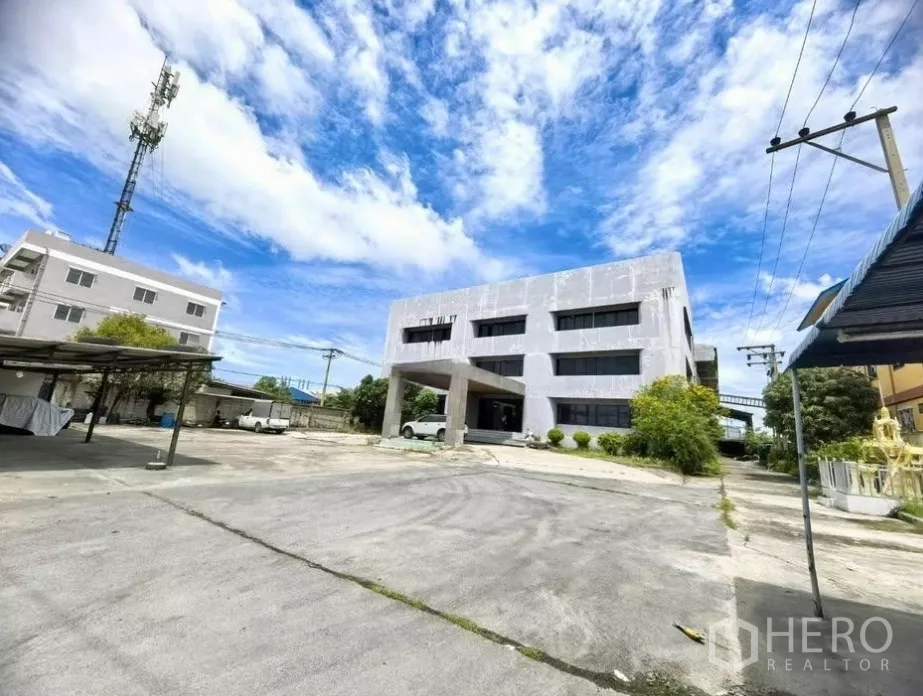 工厂 出售在Bang Phli, Samut Prakan - 三层办公楼连体厂房外观，宽阔水泥场地与停车区