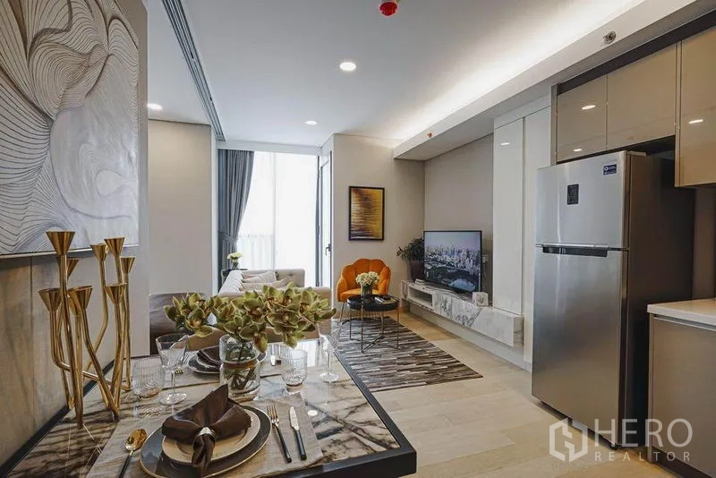 คอนโด ขายในKhlong Toei, Bangkok - โต๊ะทานอาหารข้างครัว มองไปยังห้องนั่งเล่นที่มีชั้นวางทีวีและแสงจากระเบียง