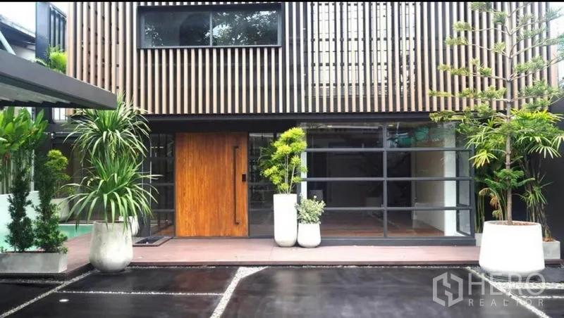 Home Office for rent or sale in Khlong Toei, Bangkok - Contemporary facade with vertical wood slats, large glass panels and planters framing the entrance.
