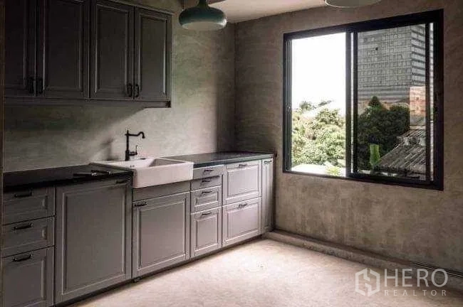 Office Space for rent or sale in Lak Si, Bangkok - Kitchenette with gray cabinetry, farmhouse sink, pendant lights, and a window.
