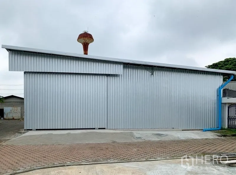 货栈 出租在Mueang Pathum Thani, Pathum Thani - 钢结构仓库侧立面，长立面、排水管与宽阔场地。
