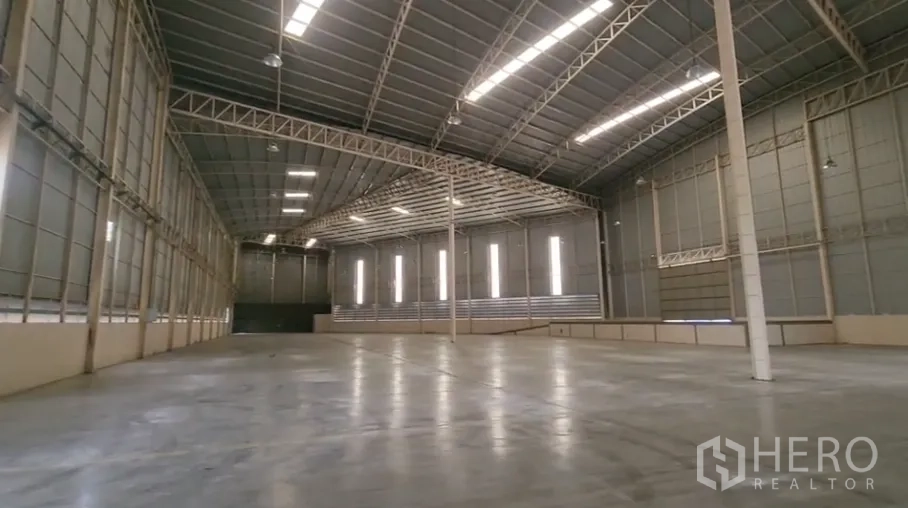 Warehouse for rent in Mueang Samut Sakhon, Samut Sakhon - Open warehouse bay showing long-span trusses, bright strip lighting, and unobstructed floor area.
