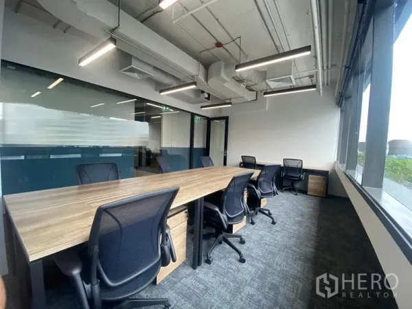Office Space for rent in Bang Rak, Bangkok - Private office with long wooden desks, mesh chairs, exposed ceiling and large windows.