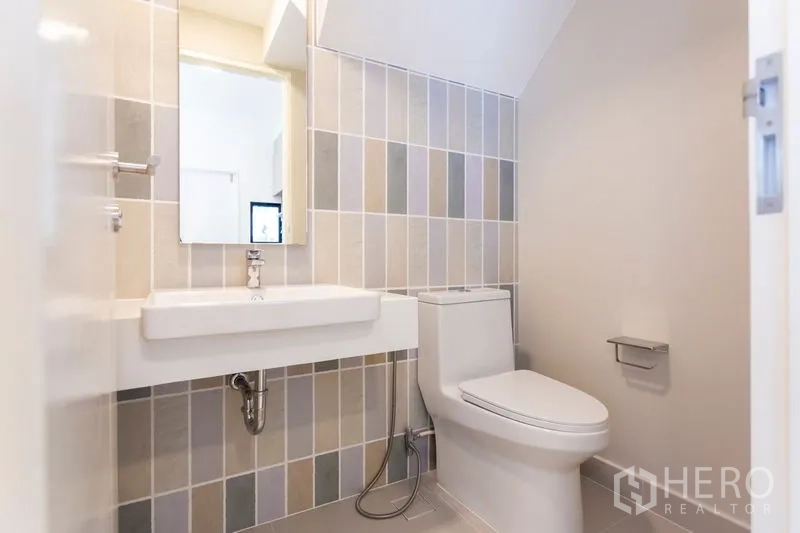 Townhouse for rent in Bang Phli, Samut Prakan - Clean bathroom with white vanity, mirror and tiled accent wall.