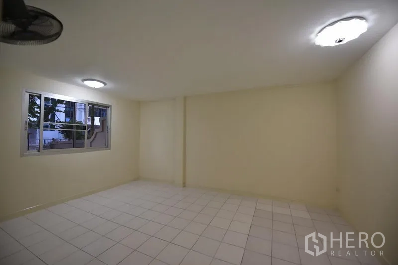 Townhouse for rent in Wang Thonglang, Bangkok - Spacious tiled room with windows and ceiling lights, ready for flexible use.