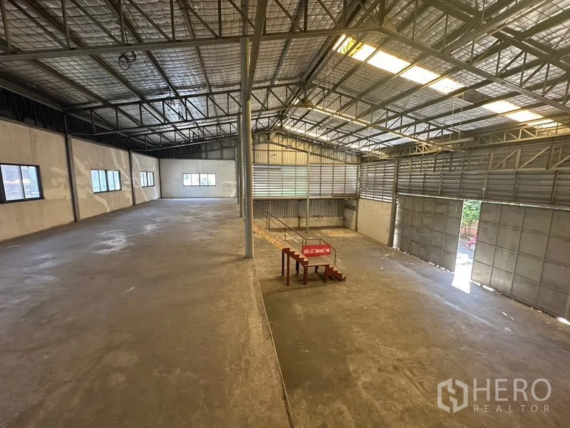 Warehouse for rent in Suan Luang, Bangkok - View from the mezzanine across the warehouse showing skylights, sliding gate and access stairs.
