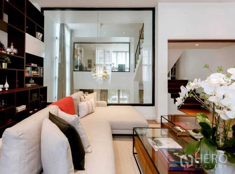 Home Office for sale in Watthana, Bangkok - Living room with sectional sofa, glass partition and display shelving overlooking void.