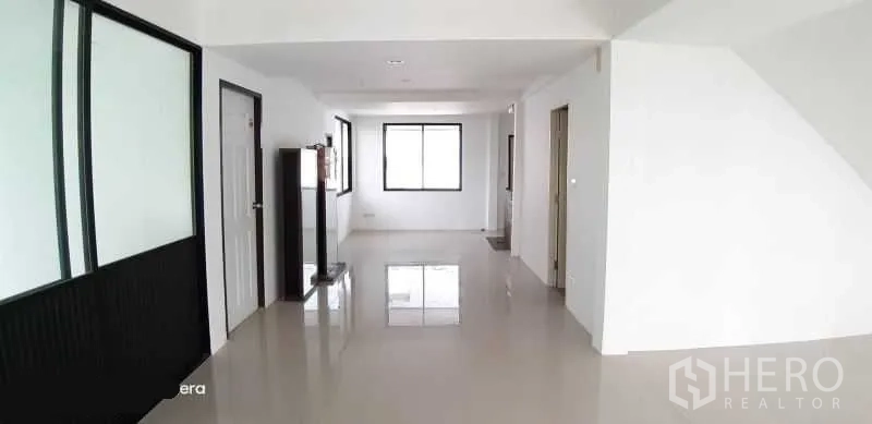 Detached House for rent in Prawet, Bangkok - Spacious hallway with windows, built-in partition and polished tile flooring.