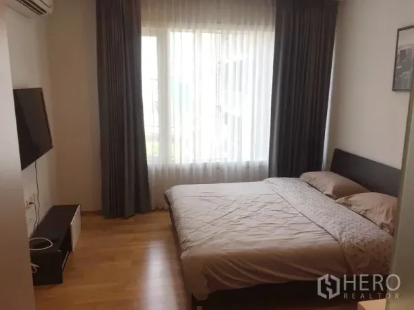 公寓 出租在Khlong Toei, Bangkok - 明亮卧室，双人床、壁挂电视与带纱帘的大窗户。