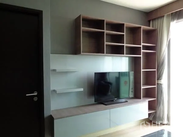 公寓 出租在Watthana, Bangkok - 客厅内的电视墙与置物架，旁有带窗帘的大窗。