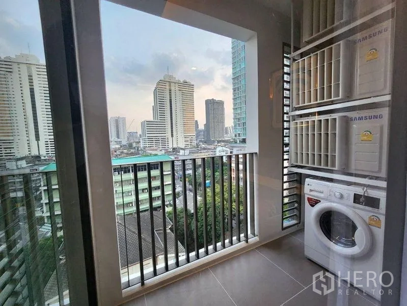 Condominium for rent in Bang Rak, Bangkok - Covered balcony with washing machine and open city skyline view.