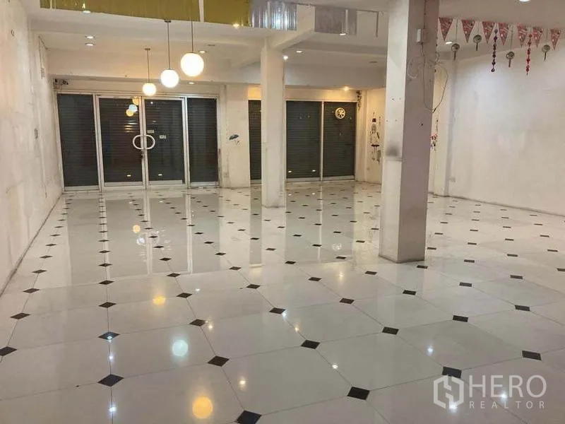 店屋 出租在Suan Luang, Bangkok - 宽敞的一层商用空间，推拉玻璃门、立柱与花纹地砖及顶灯。