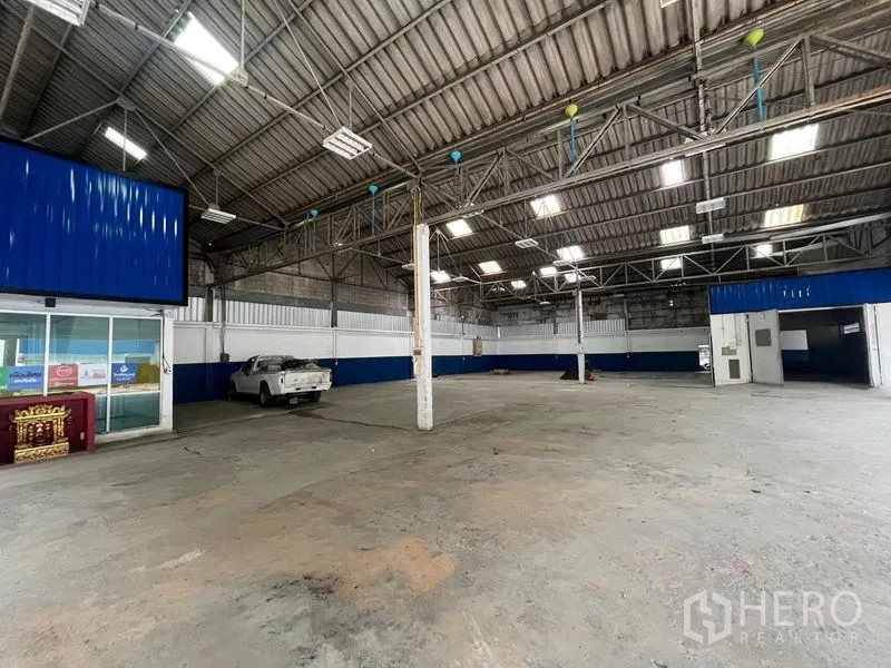 Warehouse for rent in Phra Khanong, Bangkok - Wide open factory floor with a pickup truck, LED lights, and ceiling hoist point.
