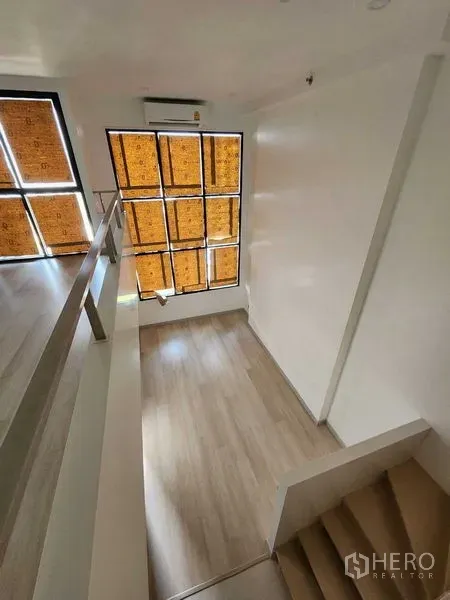 Condominium for sale in Sathon, Bangkok - View from the mezzanine over the living room with high ceiling and tall windows.