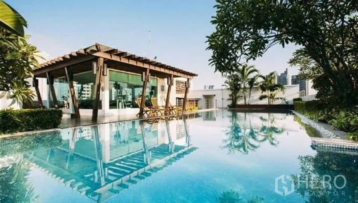 Condominium for rent in Watthana, Bangkok - Rooftop swimming pool with garden pavilion, tropical plants and city skyline backdrop.