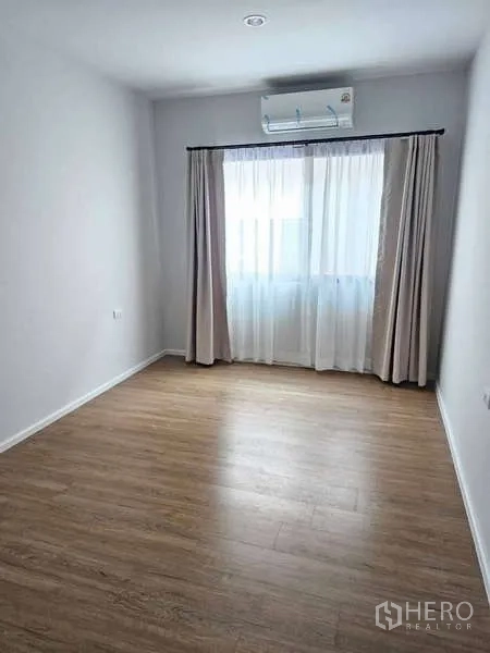 ทาวน์เฮาส์ ให้เช่าในSuan Luang, Bangkok - ห้องโปร่งโล่ง พื้นไม้ หน้าต่างพร้อมผ้าม่าน และเครื่องปรับอากาศผนัง