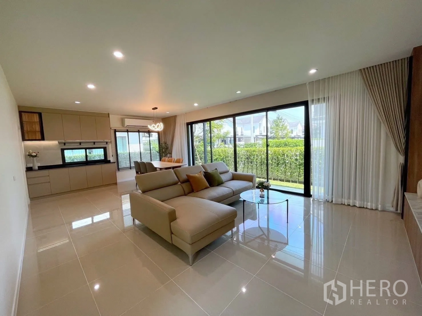 Detached House for rent in Bang Phli, Samut Prakan - Bright living–dining space opening to a small lawn through sliding glass doors and hedge fence.