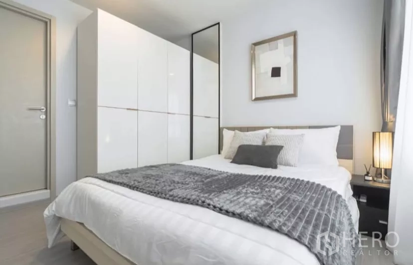 Condominium for rent in Chatuchak, Bangkok - Second bedroom angle with white wardrobe, bedside table and grey throw.