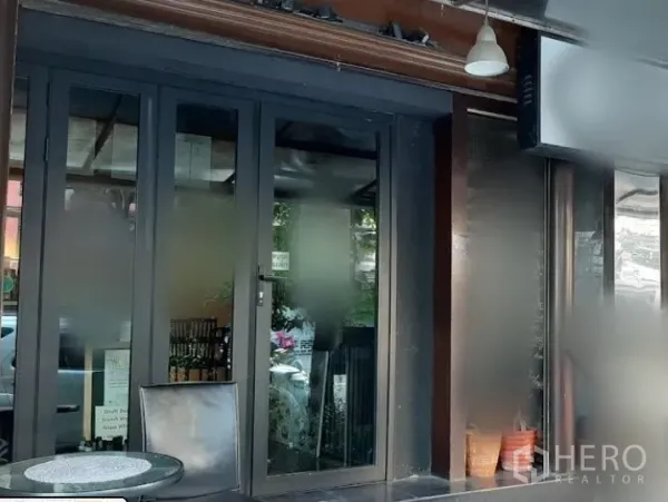 店屋 出租在Watthana, Bangkok - 通罗街区临街商铺门面，宽幅玻璃门与小型室外座位区。