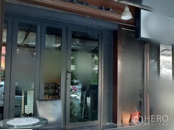 店屋 出租在Watthana, Bangkok - 通罗街区临街商铺门面，宽幅玻璃门与小型室外座位区。