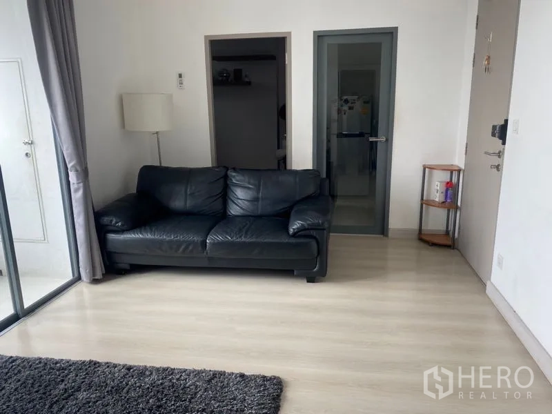 公寓 出售在Phra Khanong, Bangkok - 温馨客厅，黑色皮沙发紧邻落地移门