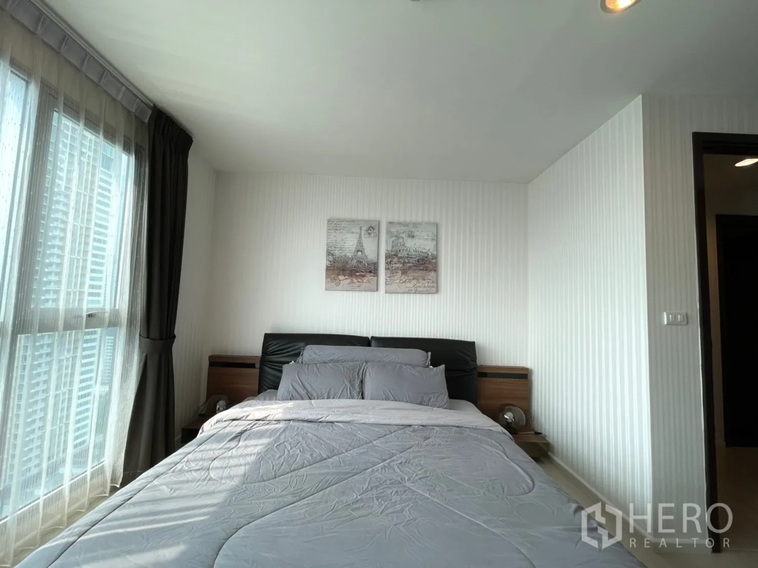 Condominium for sale in Sathon, Bangkok - Master bedroom wall with artwork above the bed and tall window with sheer curtains.