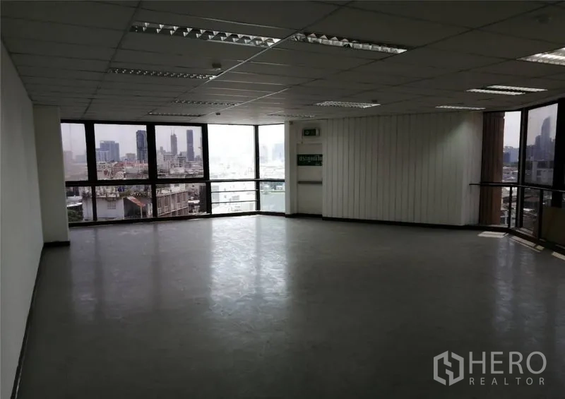 办公空间 出租在Pathum Wan, Bangkok - 宽敞办公区，转角环窗、紧急出口墙面与城市全景。
