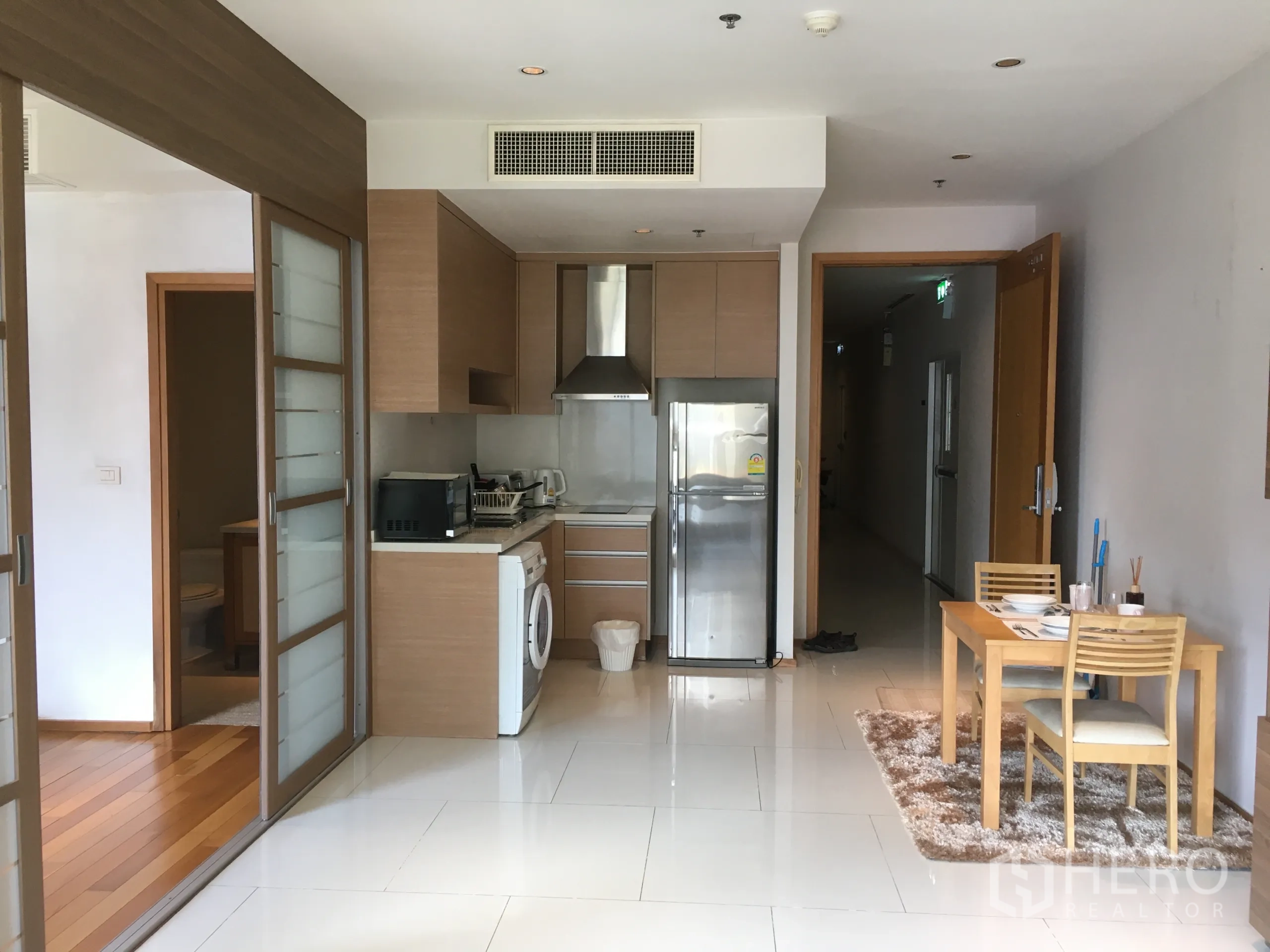 公寓 出租或出售在Khlong Toei, Bangkok - 紧凑厨房，配不锈钢冰箱、抽油烟机与小餐桌。