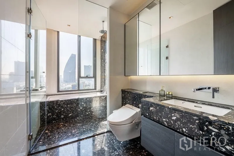 公寓 出租在Bang Rak, Bangkok - 大理石卫浴，步入式淋浴间，高窗框出城市天际线。