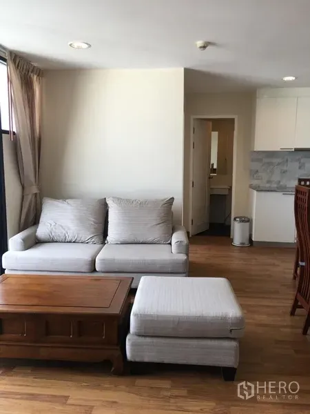 คอนโด ให้เช่าในWatthana, Bangkok - ห้องนั่งเล่นสว่างพร้อมโซฟาสีเทา โต๊ะไม้ และครัวเปิดในคอนโดเอกมัย