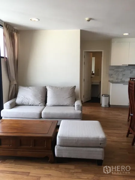 คอนโด ให้เช่าในWatthana, Bangkok - ห้องนั่งเล่นสว่างพร้อมโซฟาสีเทา โต๊ะไม้ และครัวเปิดในคอนโดเอกมัย