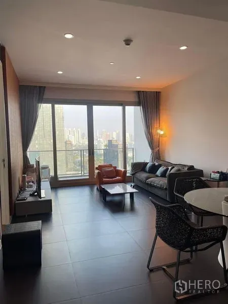 คอนโด ให้เช่าในPathum Wan, Bangkok - ห้องนั่งเล่นสว่างพร้อมหน้าต่างเต็มบาน โซฟา และวิวสกายไลน์กรุงเทพฯ