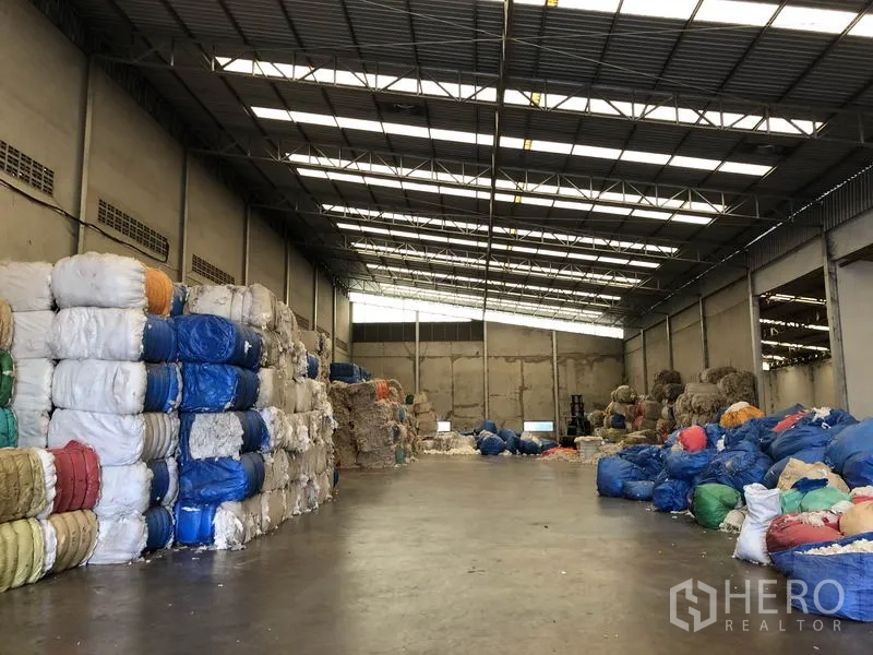 工厂 出租在Bang Bua Thong, Nonthaburi - 宽阔仓储区，清晰的大跨钢屋顶与成捆货物。