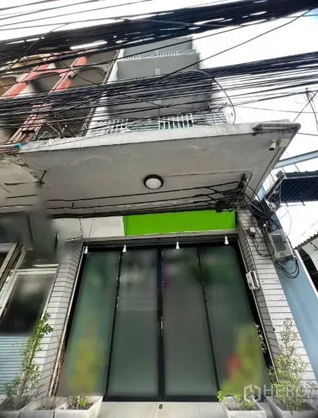 Shophouse for rent in Watthana, Bangkok - Shophouse exterior with frosted glass sliding doors, balconies and street cables.