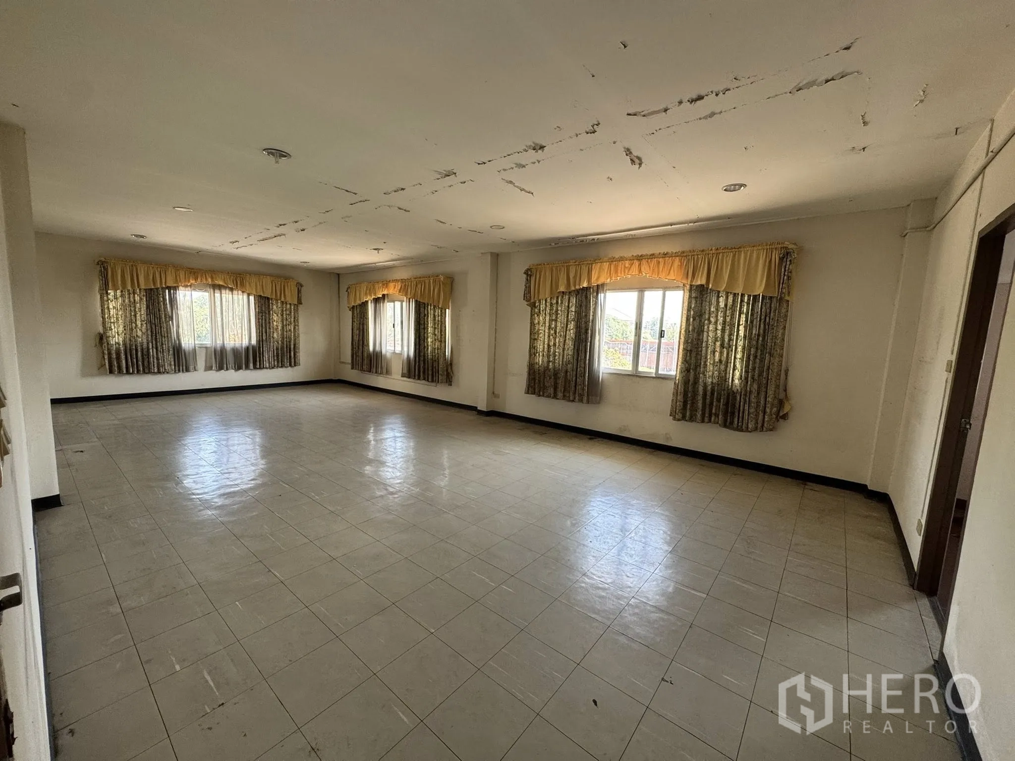 货栈 for rent in Mueang Samut Sakhon, Samut Sakhon - 大开间，黄色窗帘与瓷砖地面，天花有裂纹。