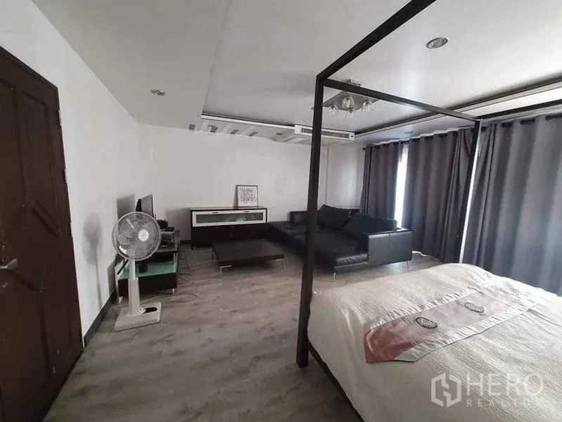 Townhouse for rent or sale in Bang Kho Laem, Bangkok - Large suite with canopy bed, leather sofa and TV console under recessed lighting.
