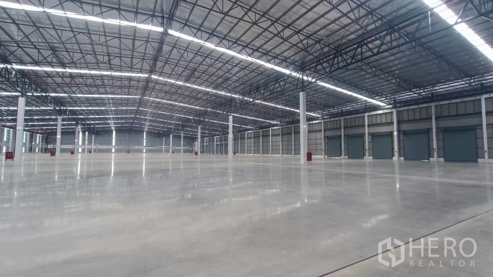 โรงงาน for rent in Bang Sao Thong, Samut Prakan - ภายในคลังสินค้าพื้นคอนกรีต เพดานสูง โครงเหล็ก และประตูม้วนหลายจุด
