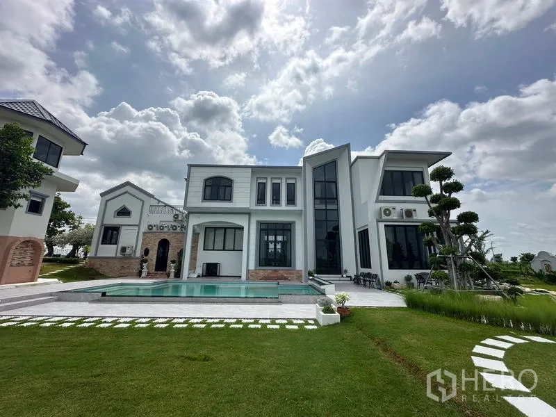 Detached House for sale in Sai Noi, Nonthaburi - Contemporary rear facade with floor-to-ceiling windows overlooking the pool and lawn.
