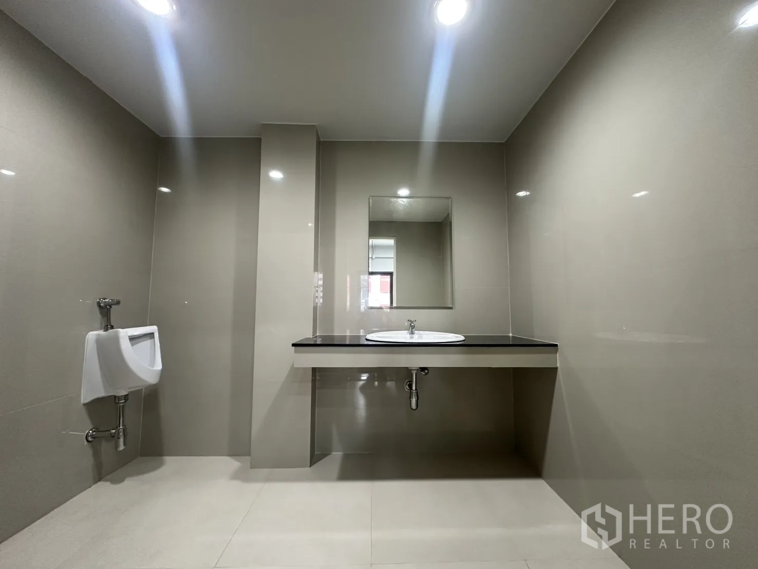 办公室 for rent in Watthana, Bangkok - 现代化瓷砖卫生间，台上盆、镜子与小便器。