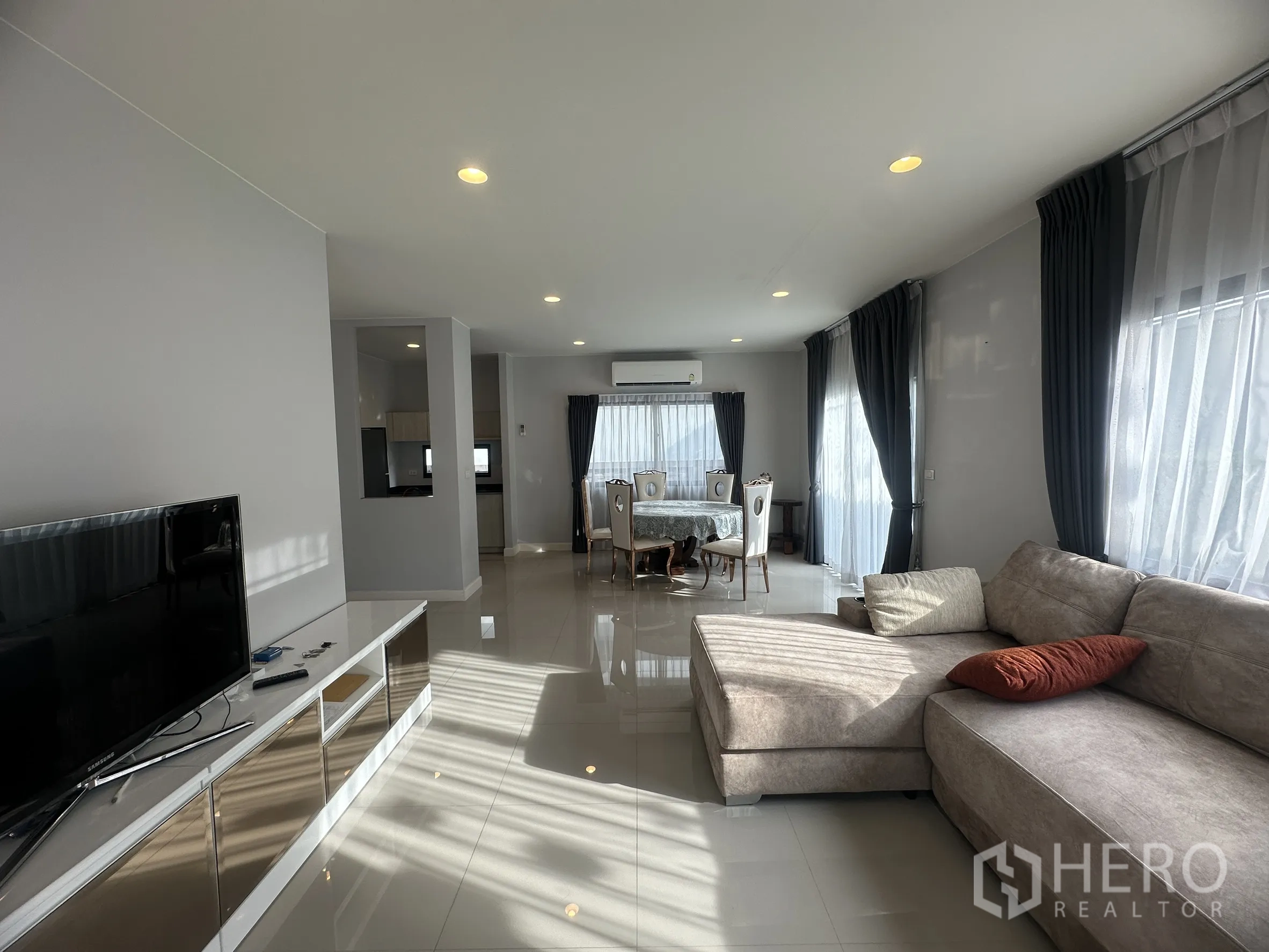 独栋房屋 for rent or sale in Lam Luk Ka, Pathum Thani - 客厅设转角沙发、电视与餐桌，旁有大窗户。