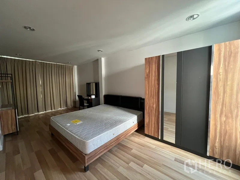 Townhouse for rent in Din Daeng, Bangkok - Spacious bedroom with laminate flooring, bed frame, wardrobe and work desk.