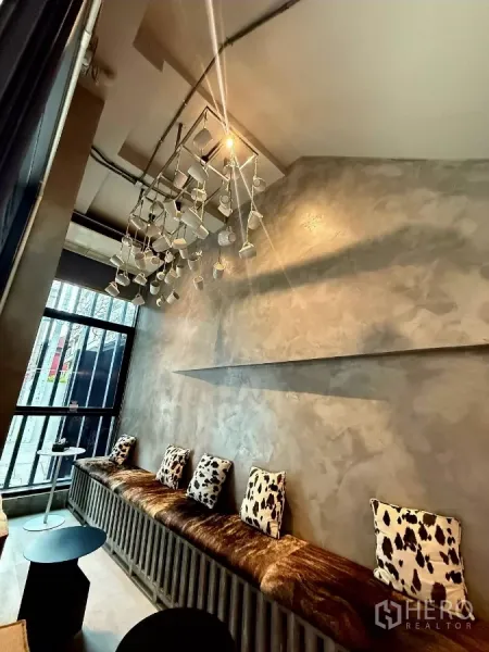 พื้นที่ขายปลีก ให้เช่าในKhlong Toei, Bangkok - ม้านั่งยาวพร้อมหมอนลายวัว ใต้โคมไฟแขวนรูปถ้วยกาแฟ ข้างหน้าต่างสูงจรดพื้น