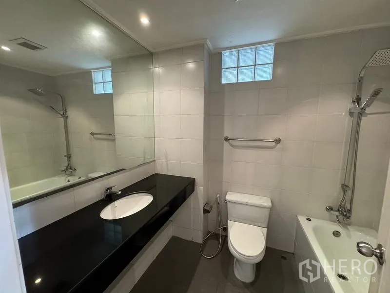 Condominium for rent in Yan Nawa, Bangkok - Bathroom featuring a long mirror, black countertop vanity and bathtub.