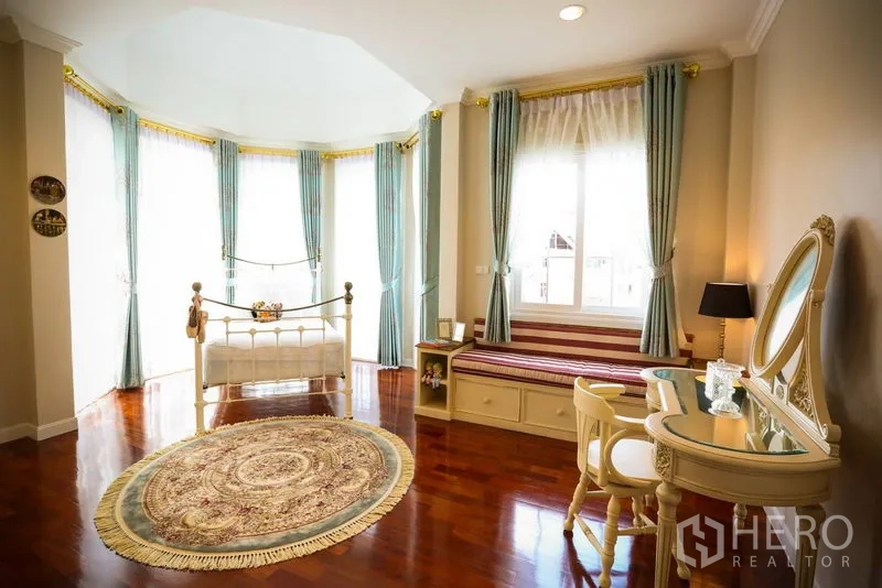 Detached House for rent in Bang Na, Bangkok - Large bay-window bedroom with classic iron bed, built-in bench and decorative rug.