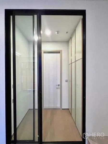 Condominium for sale - Sliding glass door to a narrow dressing area with built-in wardrobes and wood floors.