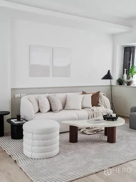 联排别墅 出租在Prawet, Bangkok - 时尚起居区，弧形米色沙发、圆形脚凳、茶几与落地灯。